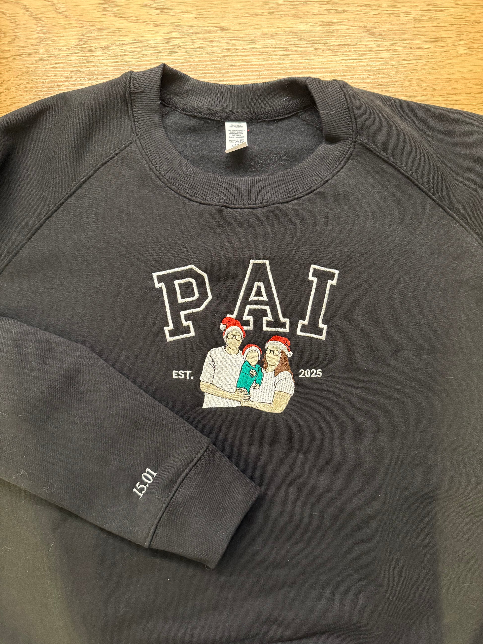 Black sweatshirt with 'PAI' text and graphic on a wooden surface