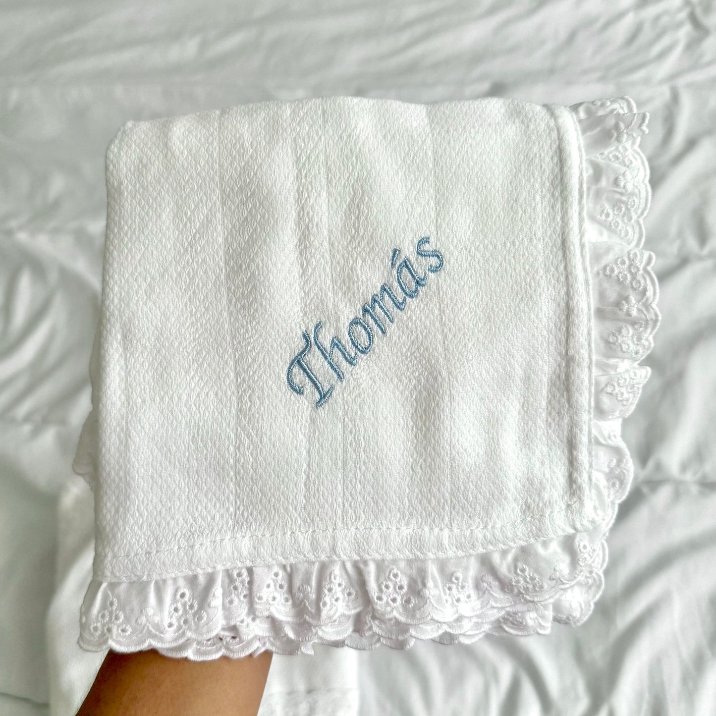 White embroidered diaper with name on a textured white background