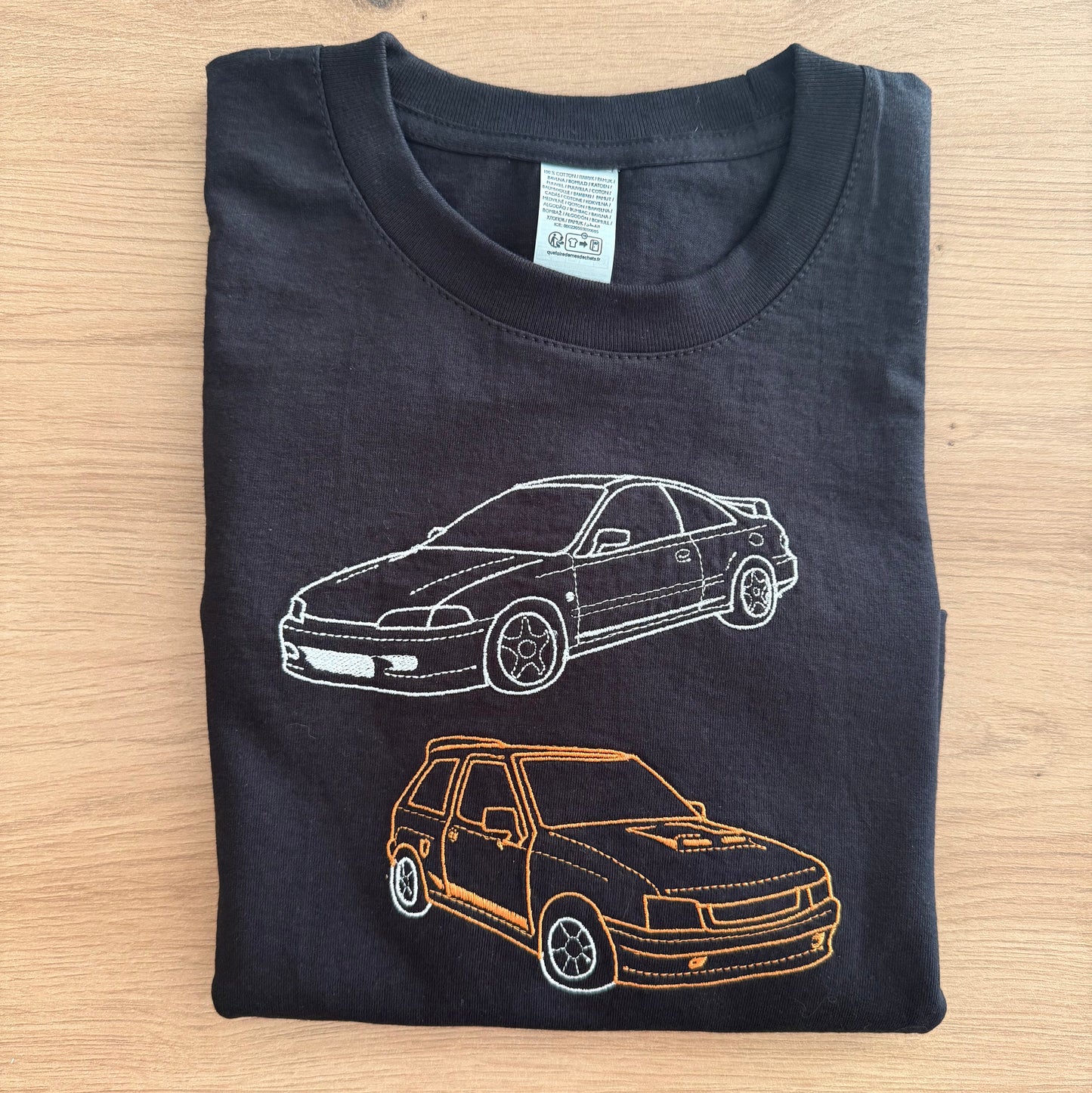 Black t-shirt with car designs on a wooden surface