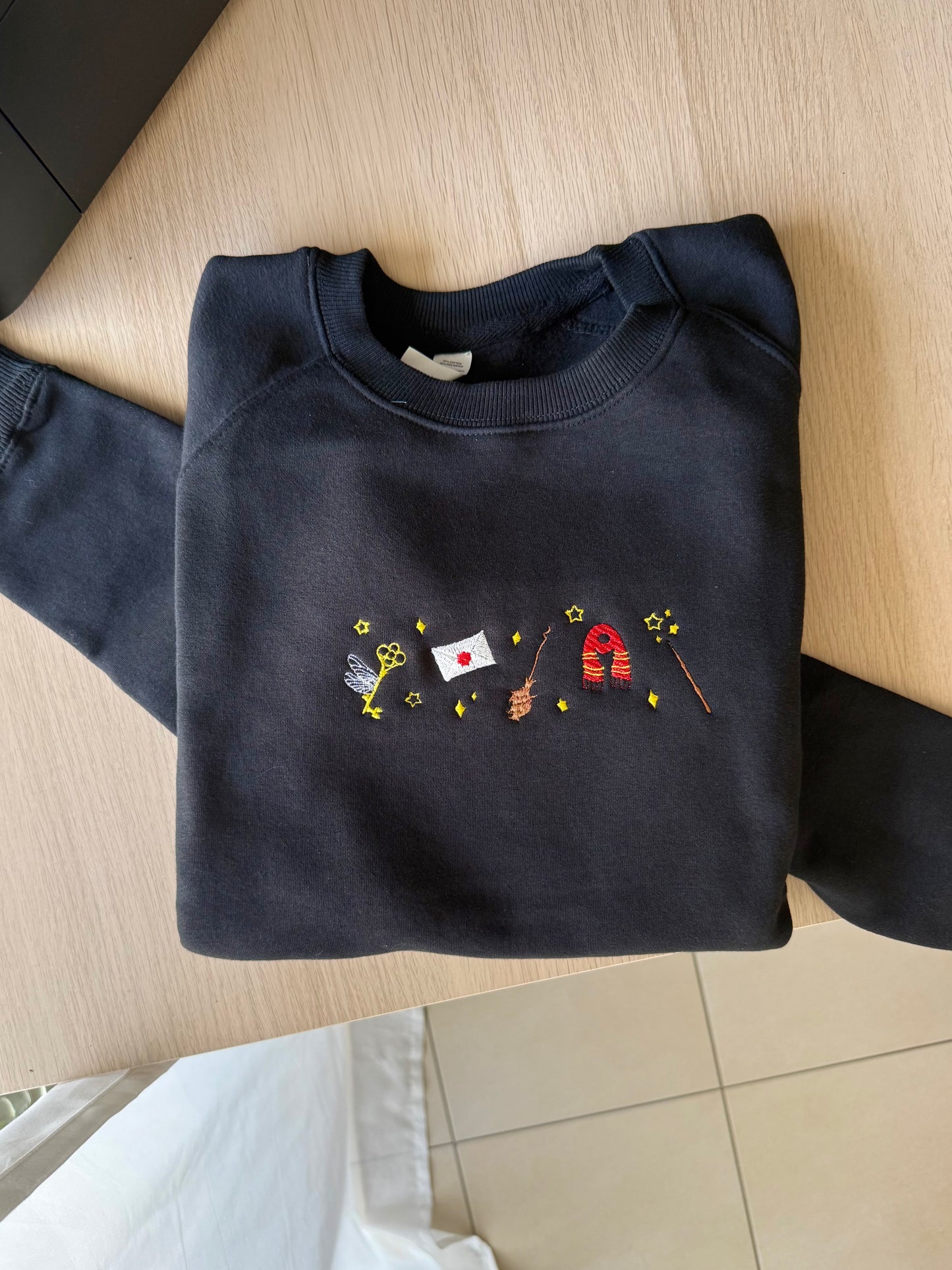 Folded navy black sweatshirt with colorful embroidery on a wooden surface