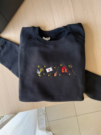 Folded navy black sweatshirt with colorful embroidery on a wooden surface