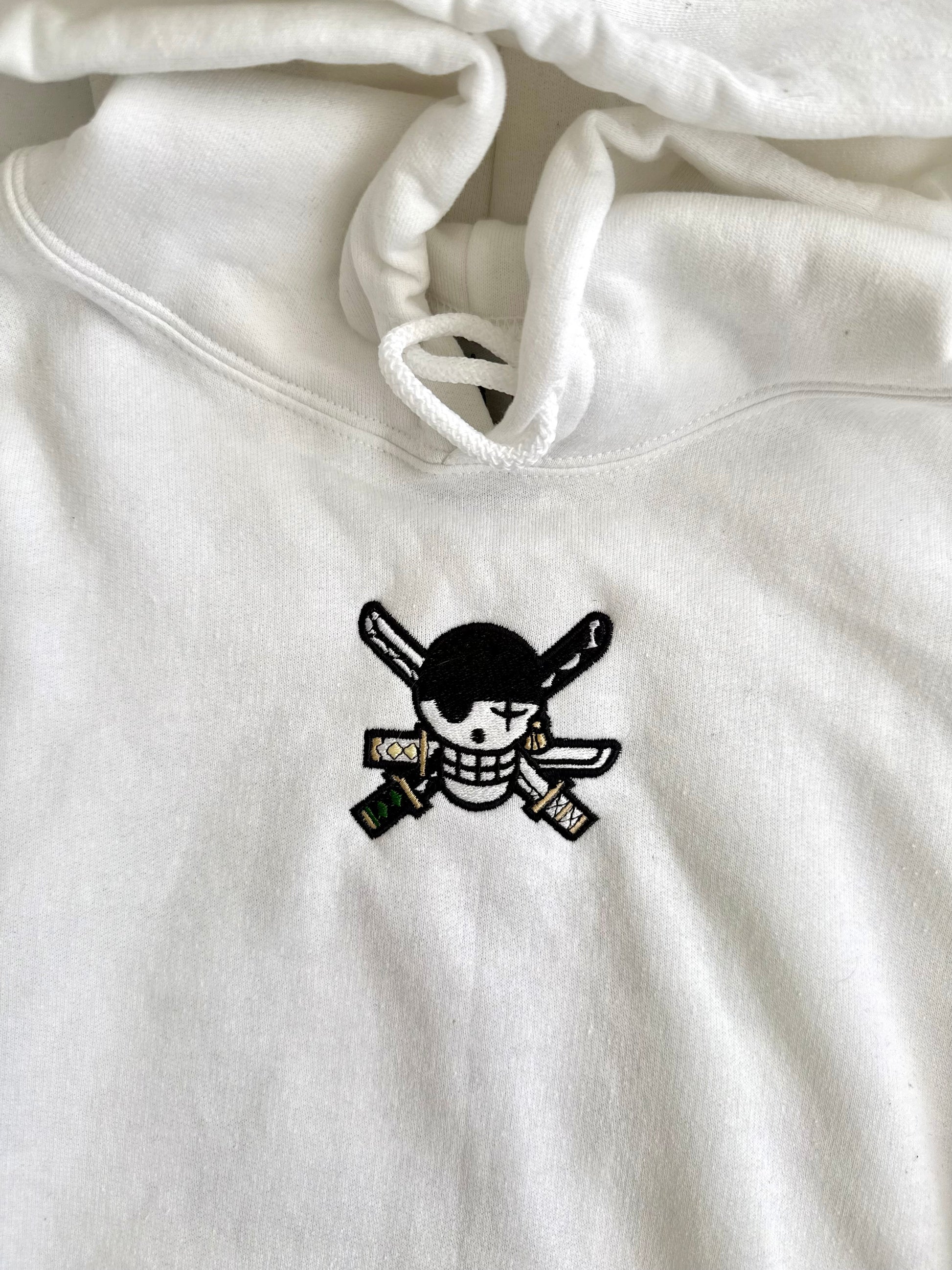 White hoodie with a black skull and crossbones design on a white background